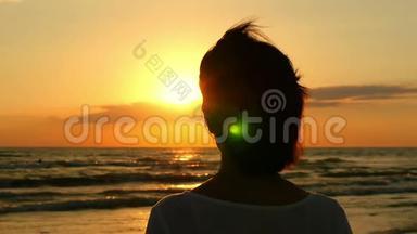 一个年轻女人看着大海的头的<strong>剪影</strong>。 一个女人看着大海的距离，夕阳和<strong>海浪</strong>